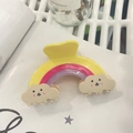 Detailed view of a rainbow hair claw clip with cute smiling cloud patterns on a book - Yellow - Large Rainbow Cloud