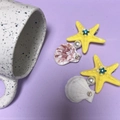 Détail de pinces à cheveux avec étoile de mer, coquillage et perle sur fond violet - Pince Latérale Étoile de Mer Perle Coquillage / Étoile de Mer Jaune