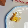 Detail of banana shaped acetate hair claw clip with colorful lettering on a white plate - Banana