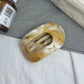 Dettaglio di un elegante fermaglio per capelli in acrilico con motivo marmorizzato - Sfumatura d'ambra