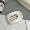 Détail macro d'une pince à cheveux en acétate crème avec un design ovale évidé marbré - Dégradé Blanc Fluide