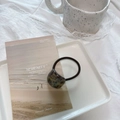 Close-up of hair tie with tortoiseshell resin charm on a minimalist ceramic tray - Glitter Gold Green