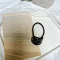 Close-up of dark tortoiseshell hair tie with black elastic band on ceramic tray - Shiny Tortoiseshell