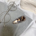 Macro view of leopard print hair clip with inlaid rhinestones and gold lettering detail - Shiny Tortoiseshell