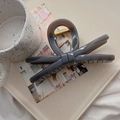 Close-up of a large dark grey bow hair claw clip made of glossy acetate with metal spring - 13.5cm / Light Silver Gray (X Bow)
