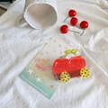 Close-up of red car-shaped hair claw clip with black dots on a white fabric surface - Cherry Cart