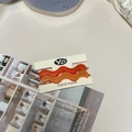 Detail of wavy acetate hair clips in orange and amber on a handmade display card - Orange + Amber