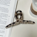 Grande molletta per capelli leopardata e tartarugata su un libro accanto a un bicchiere - 12.5CM / Tartarugato Grigio Rosa Forma Appendiabiti