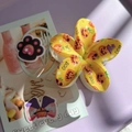 Detail of flower hair claw clip with Halloween pumpkin patterns and BOO text on purple tray - Yellow Base Pumpkin Magic Hat Flower Claw