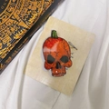Detailansicht eines glänzenden Halloween-Kürbis-Totenkopf-Handyhalters in Orange - Oranger Kürbis Skelett Klammer