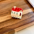 Dettaglio molletta a forma di casa rossa con pois bianchi su fondo in legno scuro - Casa Rossa