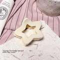 Détail d'une pince à cheveux étoile crème avec ressort en métal doré sur une carte texturée - Blanc Uni - Pince Étoile Ajourée (environ 7,5cm)