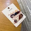 Dettaglio di 4 mollette dolci con motivi di cani, tessuto floreale e perline su una carta - Bottone Plaid Rosso - Clip Cane Schnauzer + Teddy