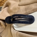 Close-up of a dark blue oval hair claw clip with golden metal spring on a white ceramic plate - Ultramarine Blue