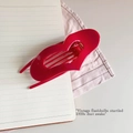 Macro detail of glossy red heart-shaped hair claw clip with metal spring on a notebook - China Red