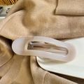 Detail of cream oval hair claw clip with glossy finish on a soft knitted sweater - Light Nude Pink