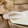 Close-up of a large cream white translucent claw clip on a soft beige knitted fabric - Jelly White