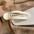 Minimalist white oval hair claw clip detail on beige knitwear and white tray - Solid White
