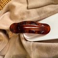 Detailed view of tortoiseshell resin hair claw on ceramic plate with knit background - Shiny Tortoiseshell