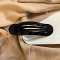 Glossy black hair claw clip with triple hollow design on a minimalist ceramic tray - Bright Black
