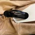 Matte black oval hair claw clip shown on a white ceramic plate and knit sweater background - Matte Black