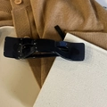 Nahaufnahme einer glänzend tiefblauen Schleifen-Haarklammer auf neutralem Textilstoff - Hellschwarz