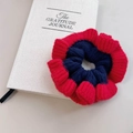 Chouchou en laine tricotée rouge et bleu foncé contrasté posé sur un livre blanc - Red-Royal Blue