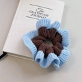 Détail du chouchou tricoté bleu et marron avec texture à volants doux sur un carnet - Sky Blue-Chocolate