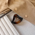 Detail der Haarklammer in Schildpatt-Optik mit Bernsteinmuster auf neutralem Stoff - Helles Französisch
