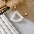 Detail einer eleganten weißen Haarklammer aus Acetat mit goldener Feder auf Tablett - Gelee Weiß
