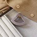 Detail einer 6 cm hohen Haarklammer in Mauve mit goldener Feder auf Stofftablett - Steingrau