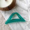 Detailed macro shot of a clear cyan hollow triangular hair claw clip on soft white fabric - Lake Blue