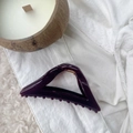 Macro shot of large purple triangular hair claw clip with golden metal spring details - Deep purple