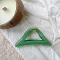 Detail view of a green triangular hair claw clip on white lace and rug background - Bean Green
