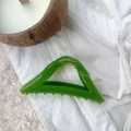 Macro shot of transparent emerald green triangular hair claw clip with golden metal spring - Turquoise Green