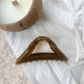 Detail view of large amber resin triangle hair claw clip on lace and candle - Mustard Yellow