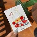 Pair of tomato-themed acrylic hair clips in yellow and white on a display card - Three Tomatoes Drop Clip