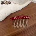 Close-up of a red polka dot acetate hair comb with 11 silver metal teeth on wood surface - Red with White Polka Dots