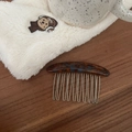 Detail of tortoiseshell acetate hair comb with silver metal teeth on a wooden surface - Blue Floral Tortoiseshell