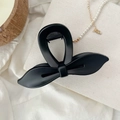 Gros plan d'une pince à cheveux papillon noir mat sur un fond esthétique élégant - Noir Mat