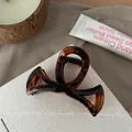 Détail de la pince à cheveux en écaille de tortue sur tissu texturé blanc - 8.5cm / Ambre