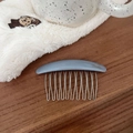 Close-up of a blue acetate hair comb with silver metal teeth on a wooden surface - Grey Blue