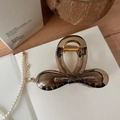 Close-up of brown translucent bow hair claw clip with golden metal spring on desk - Transparent Brown