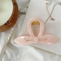 Détail d'une pince à cheveux nœud rose avec ressort doré sur un fond en tissu doux - Calicot Blanc