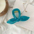 Détail de la pince à cheveux noeud bleu avec ressort en métal doré sur tissu blanc - Vert malachite