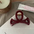 Detail of burgundy resin hair claw clip with golden spring on beige fabric - Ancorra Red