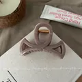 Close-up of pink resin bow hair claw clip with golden spring mechanism and glossy finish - Stone Grey