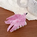Detailed view of an elegant pink pearlescent bird-shaped hair claw on a wooden surface - Pink Swallow
