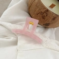 Detail shot of a translucent pink square hair claw clip with golden metal spring - 5.2cm / Jelly Pink