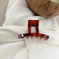 Detailed close-up of dark brown tortoiseshell hair claw clip on white lace fabric - 5.2cm / Shiny Tortoiseshell